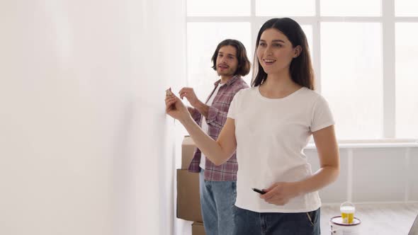 Married Man and Woman Measuring Wall with Tape Together Doing Home Improvement and Renovation