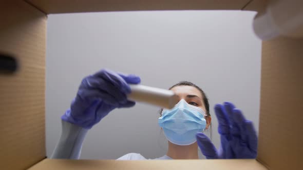 Woman in Mask Unpacking Parcel Box with Cosmetics