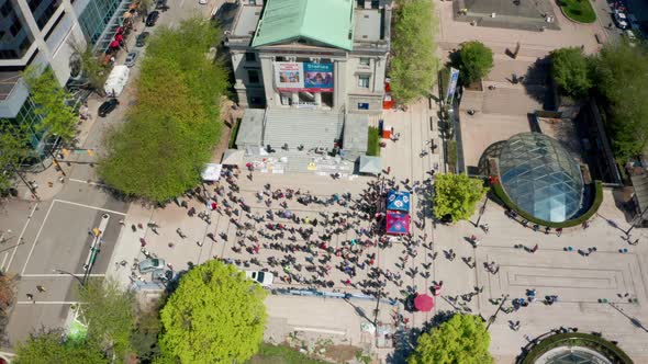 Aerial view of Vancouver art gallery, wide daytime orbit shot in 4k. Old building looms over crowd o