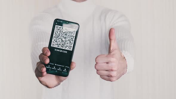 Man Shows QR Code on Smartphone and Shows ThumbsUp Sign on White Background