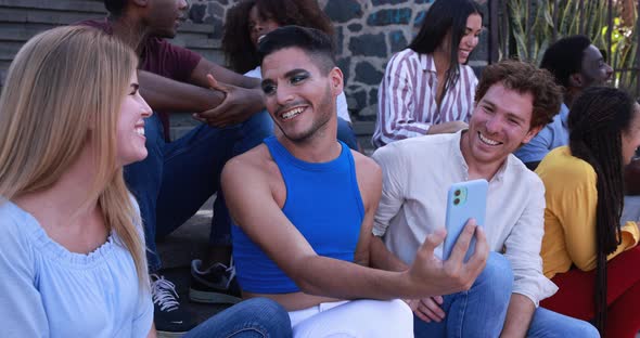 Young diverse people having fun in the city while using mobile phone