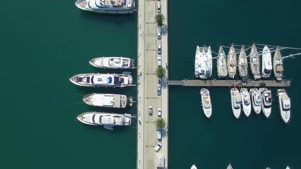 Car Moving Among Pier With Luxury Yachts and Sailboats