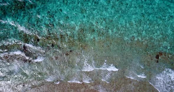 Daytime drone travel shot of a white sandy paradise beach and blue water background in colorful 