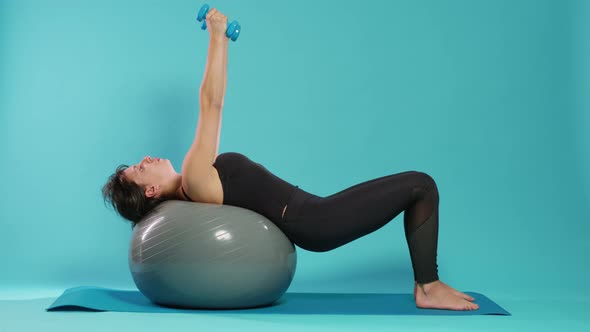 Active Woman Lifting Dumbbells on Fitness Toning Ball