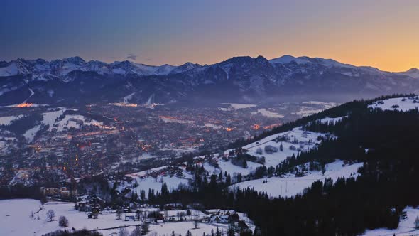 Dusk over snowy zakopane in winter at night, aerial view