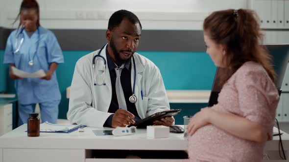 General Practitioner Using Digital Tablet at Consultation with Future Mother