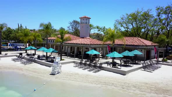 Aerial pan of front of a lake clubhouse at a community sand lagoon pool