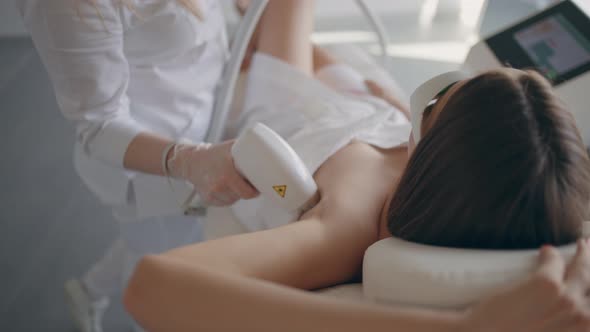 Laser Hair Removal of Armpit of Female Client in Modern Beauty Salon Young Woman is Lying in