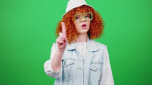 Young Redhead Woman Wearing Eyeglasses and Panama Hat Shaking Head in Rejection and Shaking Fingers