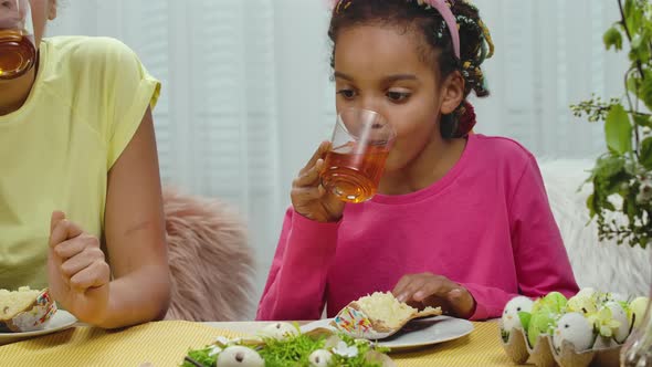 Mom and Daughter with Funny Bunny Ears are Drinking Tea with Easter Cake