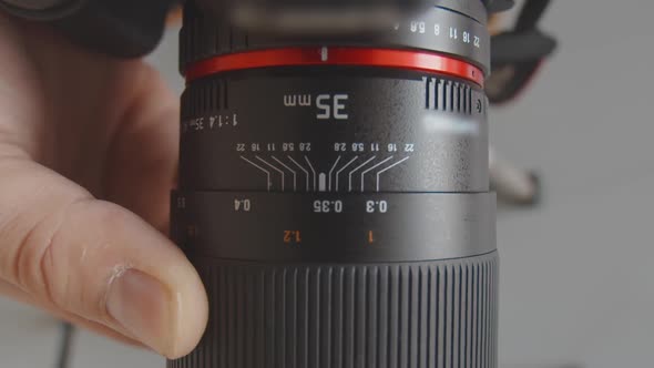 A Man's Hand Turns the Focus Wheel on the Lens. Close-up of the Focus Wheel Setting on the Lens