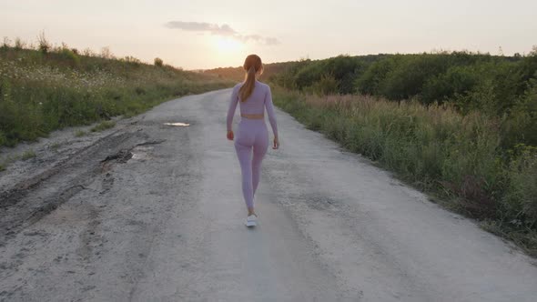 Back Side View of a Young Girl That Walks on Road