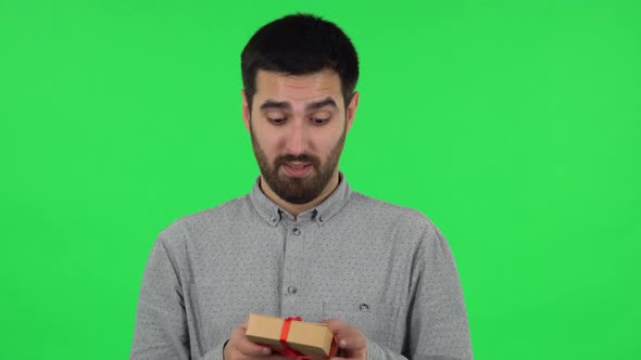 Portrait of Brunette Guy Is Opening the Gift, Surprised and Rejoicing. Green Screen