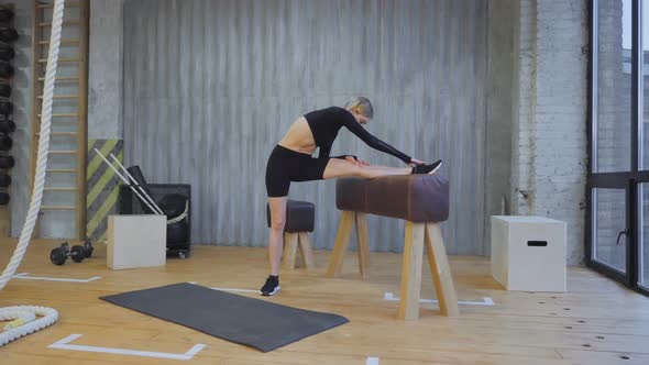 Athletic Woman Does Muscle Stretching on A Sports Horse in The Gym. Athletic Girl Does Sports