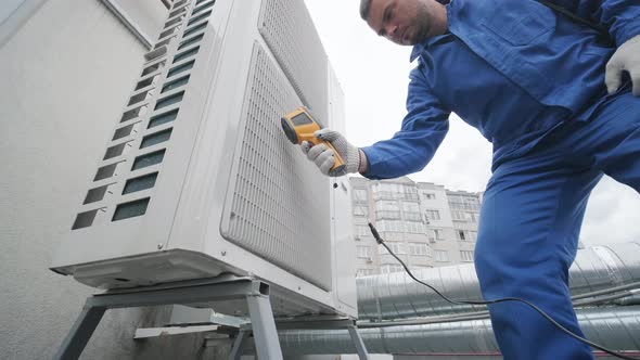 Technician uses a thermal imaging infrared thermometer to check the condensing