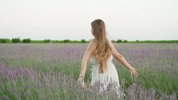 Beautiful Young Woman Runs on the Green Lavender Field
