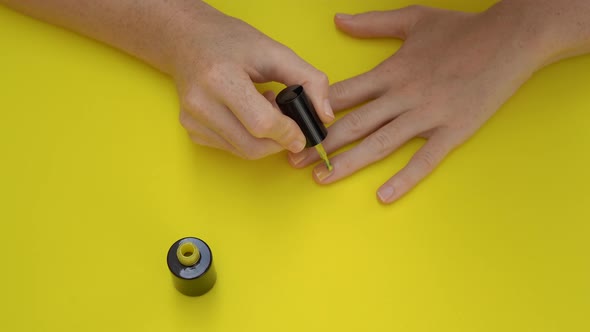 Closeup Shot of a Girl That Paints Her Nails in Yellow on a Yellow Background. Yellow Concept