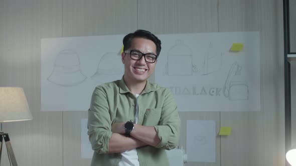 Asian Man Designer Cross Arms And Smile To Camera While Standing In Front Of Bag Design Sketch Paper