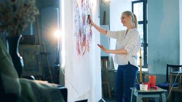 Art Studio with a Blond Lady Painting with Her Hands and Smiling