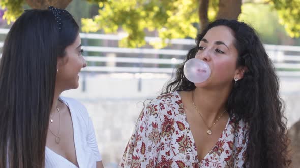 Happy Multiethnic Teenage Girls Blowing and Popping Bubbles in Park