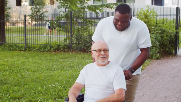 African-American caregiver and old disabled man in a wheelchair. Nurse and patient.