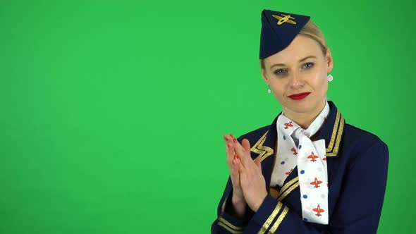 A Young Beautiful Stewardess Applauds and Smiles at the Camera - Green Screen Studio
