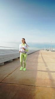 Sportswoman Running on Embankment in Morning