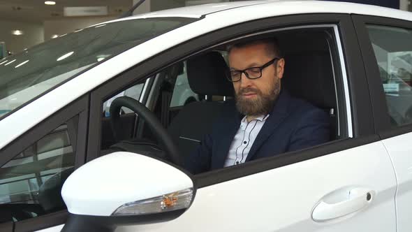 Male Customer Examines Car Interior at the Dealership