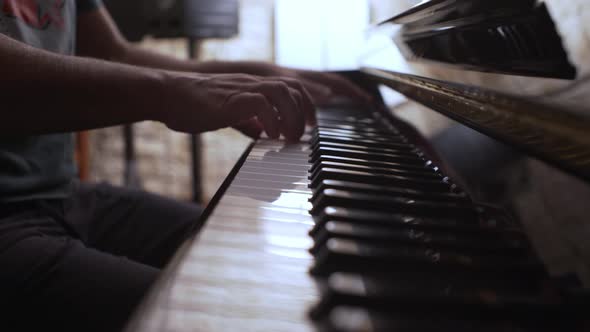 Male musician plays an old vintage Yamaha piano, side view with shallow depth of field 4K
