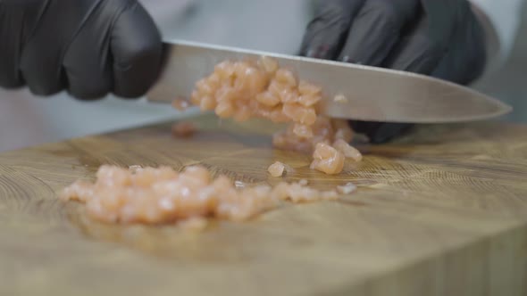 Hands of Chef in Restaurant Uniform and Black Gloves Cutting Slices of Tuna fish