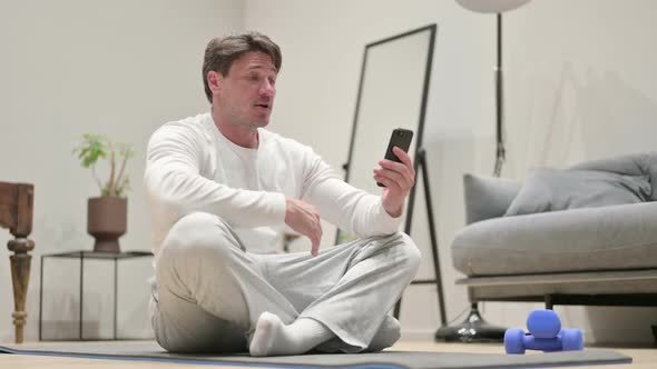 Man Talking on Video Call on Smartphone on Yoga Mat