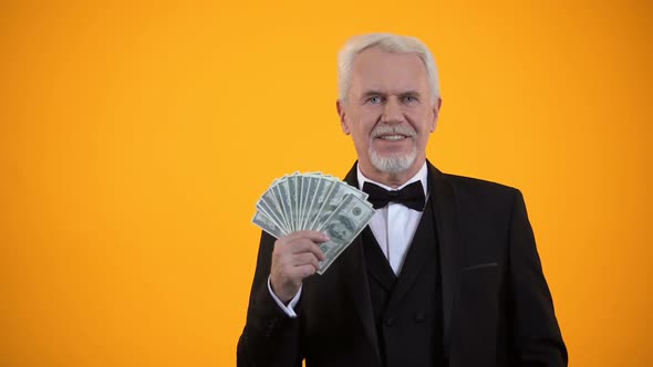 Joyful Senior Man Pointing Finger on Dollars, Casino Winner, Banking and Finance