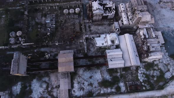 Ruins of a destroyed and creepy factory left abandoned, Drone top down shot above the misty clouds