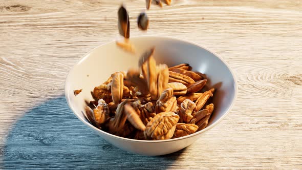 Falling down pecan nuts is filling up the ceramic bowl. Tasty crunchy nuts.Snack