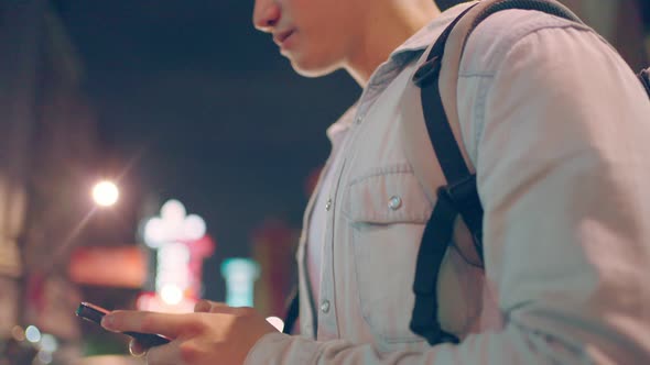 Close up of Asian man backpacker chatting on mobile phone walk in city.