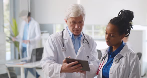 Multiethnic Male and Female Physicians Tapping and Scrolling on Digital Tablet