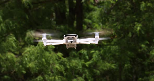 White Small Copter Flying on the Background of a Tree