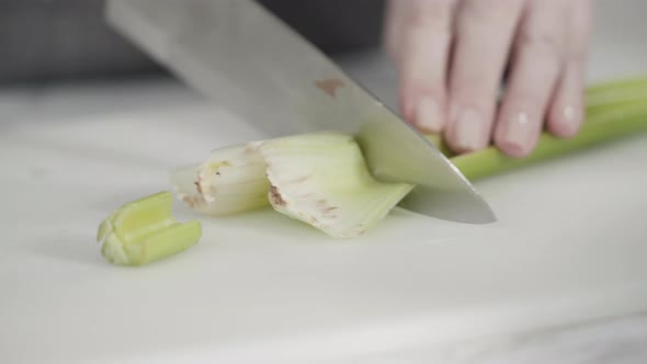 Curring vegetables on a white cutting board to cook vegetarian white bean soup.