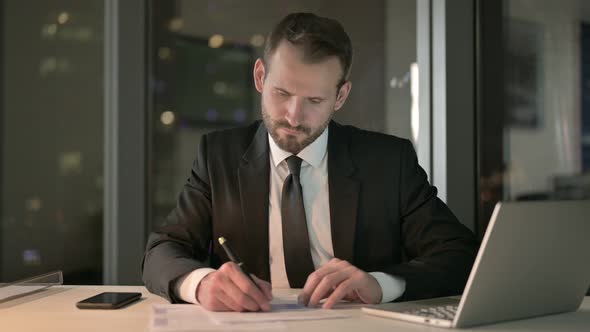 Handsome Businessman Checking Document in Office at Night