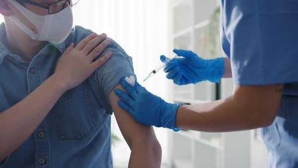 Young lady nurse giving Covid-19 or flu antivirus vaccine to patient wear mask at hospital