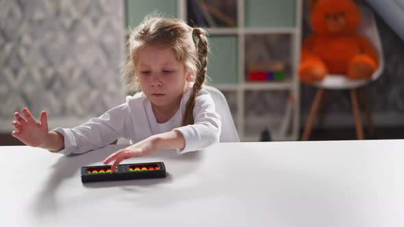 Bored Little Girl with Plaits Turns Abacus at Workplace