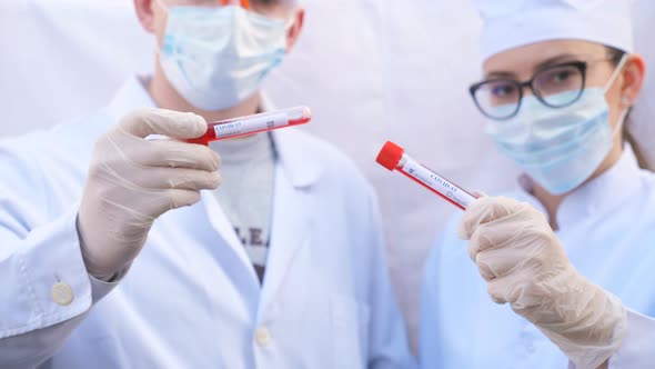 Male and Female Doctors Holds Test Tube with Blood Sample to Coronavirus