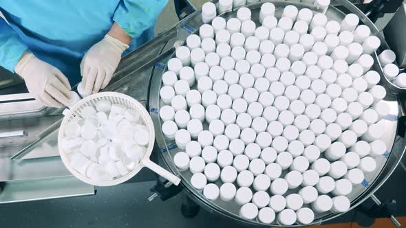 Pharmacology Worker is Closing Pill Jars on the Conveyor