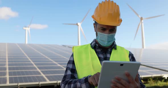 Young man working with digital tablet while wearing safety mask at wind farms