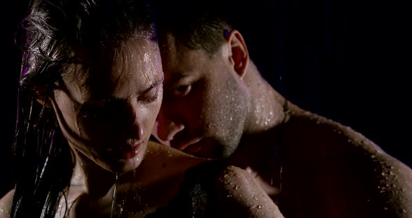 Portrait of a Passionate Beautiful Couple with Bare Shoulders, Which Are Under Heavy Rain on a Black