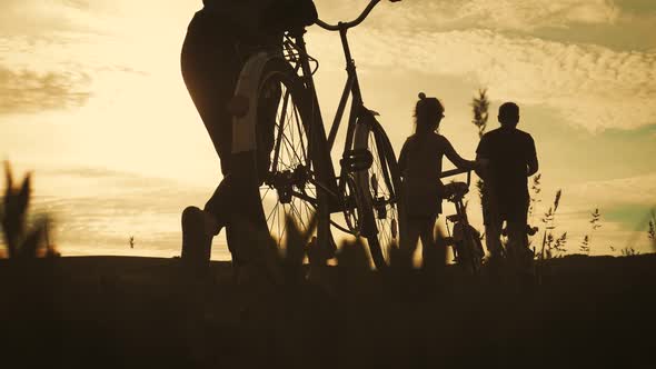 Biker Family Silhouette, Parents with Two Kids on Bikes at Sunset