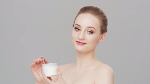 Studio portrait of young, beautiful and natural woman over grey background.