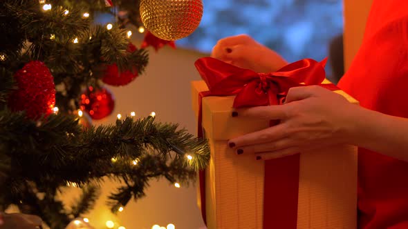 Woman Taking Gift Box From Under Christmas Tree