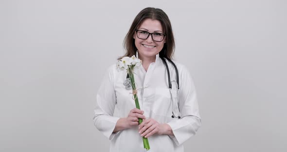 Smiling Mature Woman Doctor Nurse with Bouquet of Flowers, Gift, Celebration, Medical Worker Day