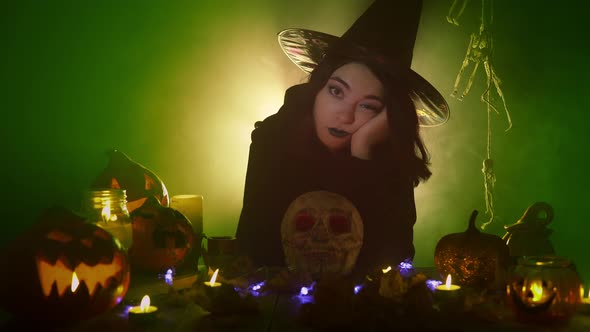 Bored Witch Sits Surrounded By Jack O'lanterns and Skull